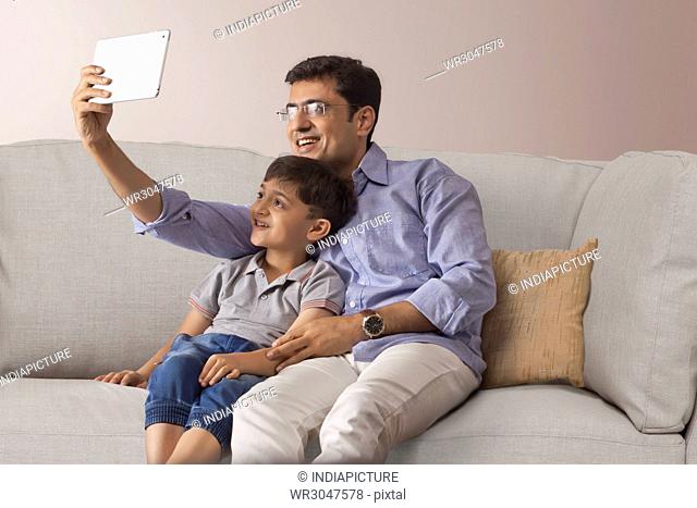 Happy father and son taking selfie with digital tablet