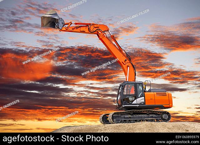 excavator working on construction site in front of dramatic sky