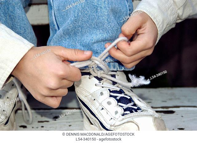 Four years old boy learning to tie shoes