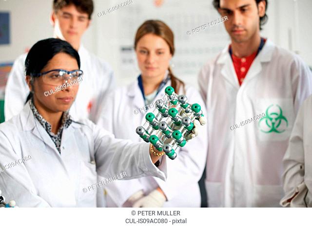 Chemistry teacher and students holding molecular model