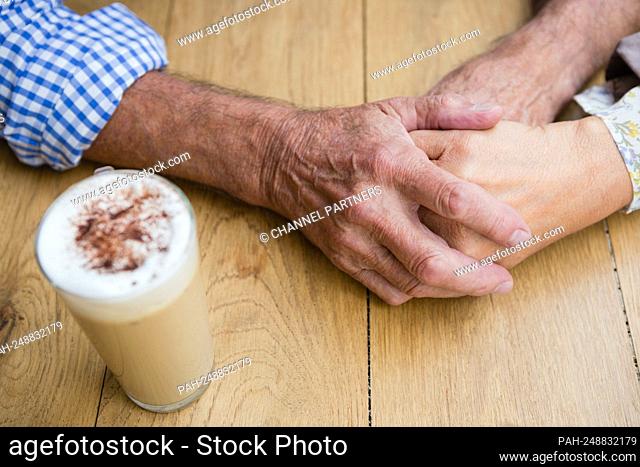 Romantic senior couple holding hands in outdoor cafÃ © || Model approval available