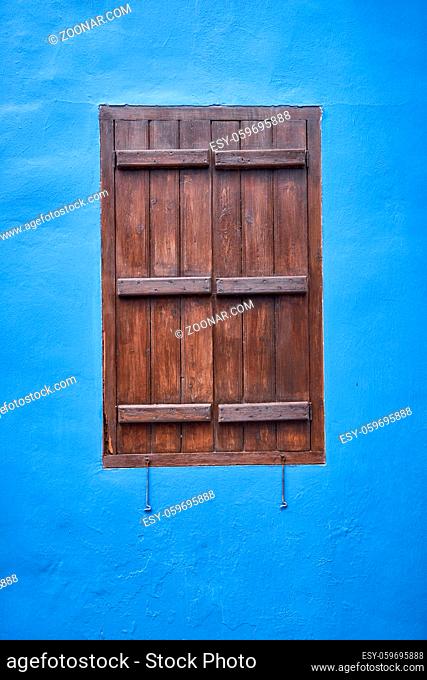 The view of the window with the wooden brown shutter in the wall which is painted blue ? a common color in Cyprus. Pano Lefkara village. Cyprus