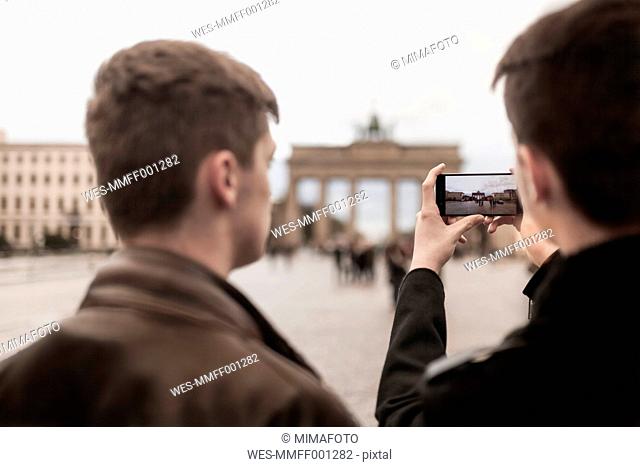 Two teenagers taking a smartphone image of the Brandenburg Gate in Berlin