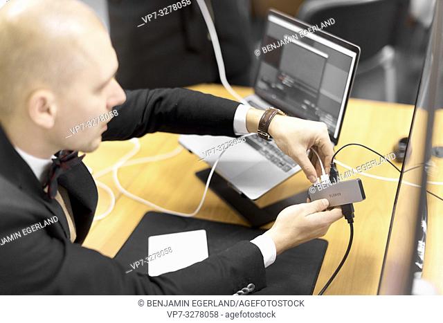business man plugging USB cable in USB port hub, next to laptop, in office, in Cottbus, Brandenburg, Germany