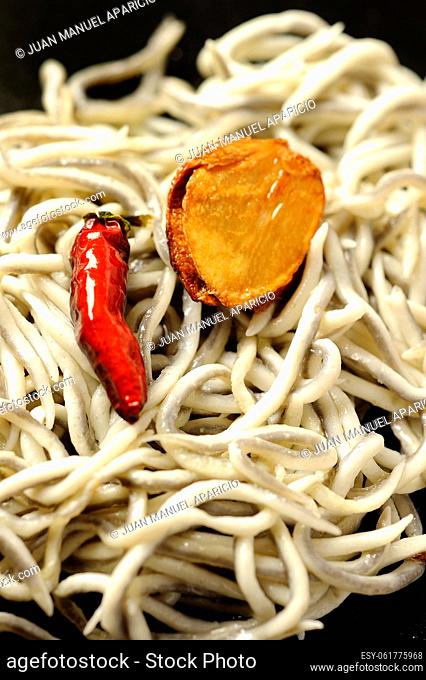 Gulas, surimi based imitation (not authentic) elvers, with garlic and chilli on black background