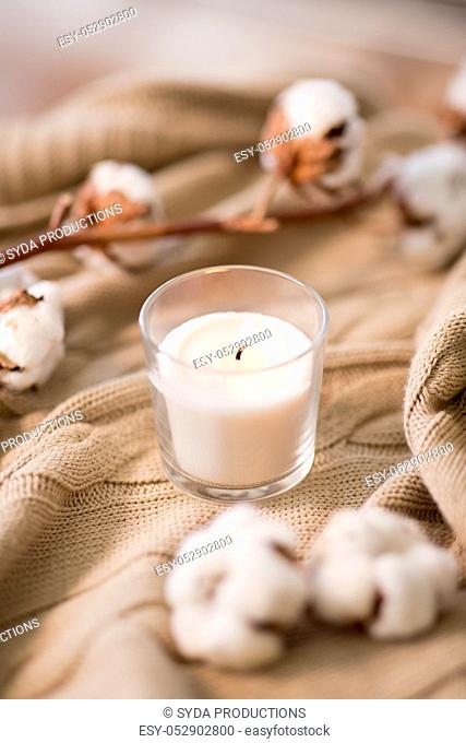 burning candle and cotton flower on blanket