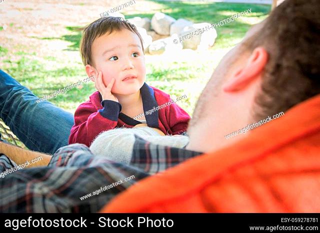 Mixed Race Boy Having Fun Outside While Parents Talk To Him From Hammock
