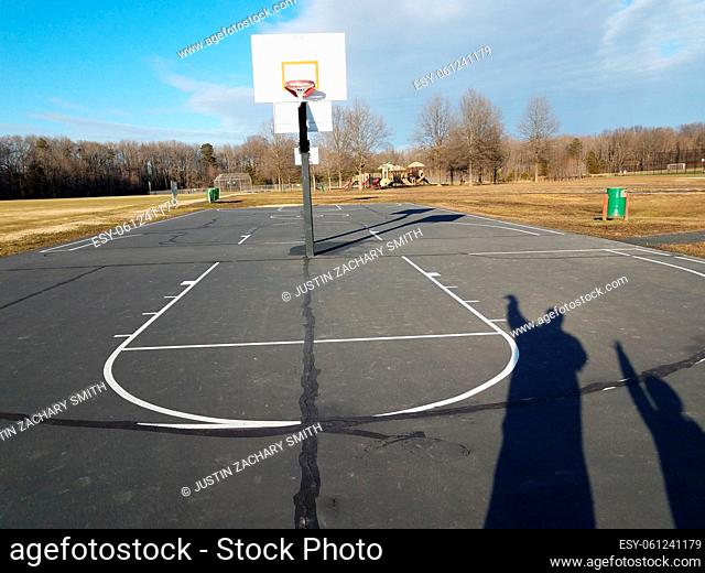 father and son shadows on basketball court at park
