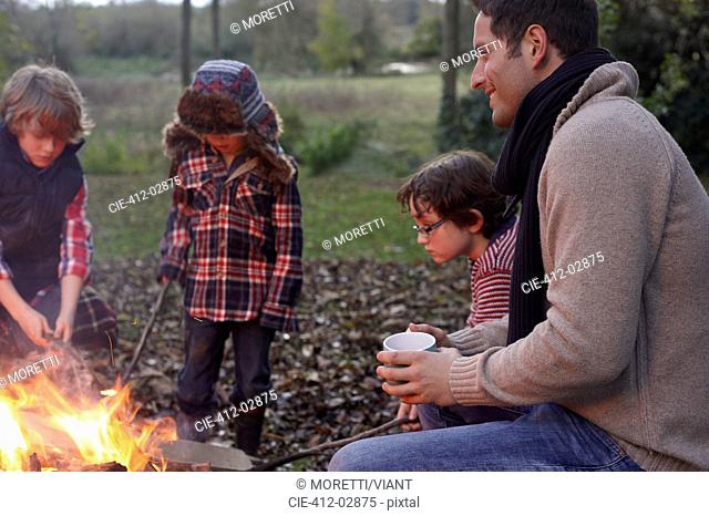 Father and children sitting around bonfire