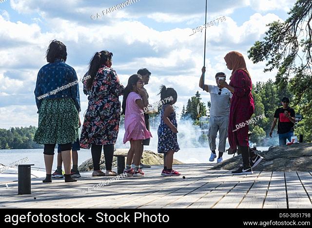 Stockholm, Sweden A family from Bangladesh picknicking on a dock catch a fish in the water