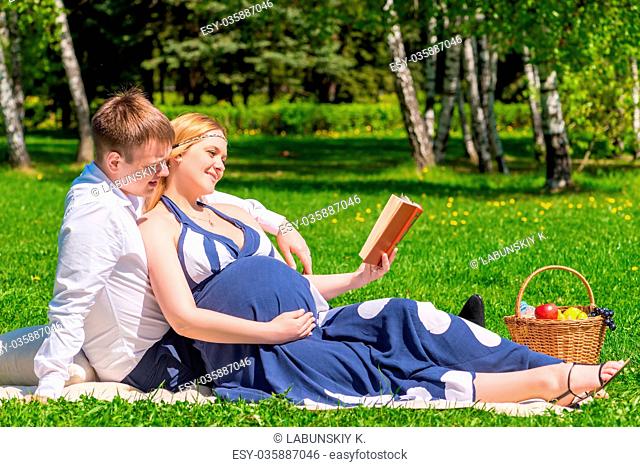Future young parents reading the book on picnic for children