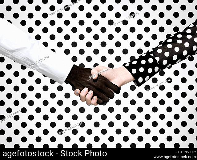 Multiethnic handshake on polka dot background