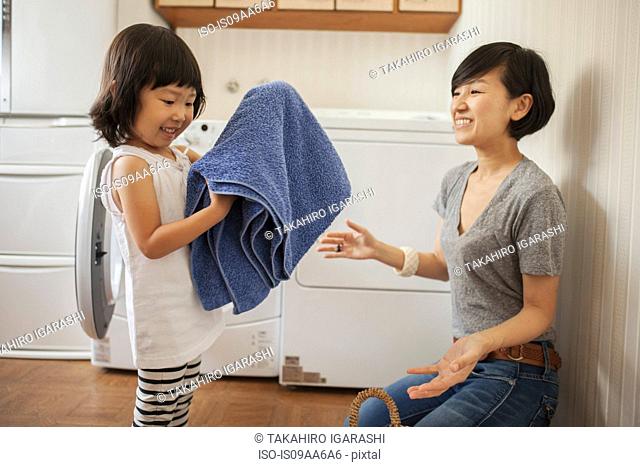 Mother and daughter, girl folding towel
