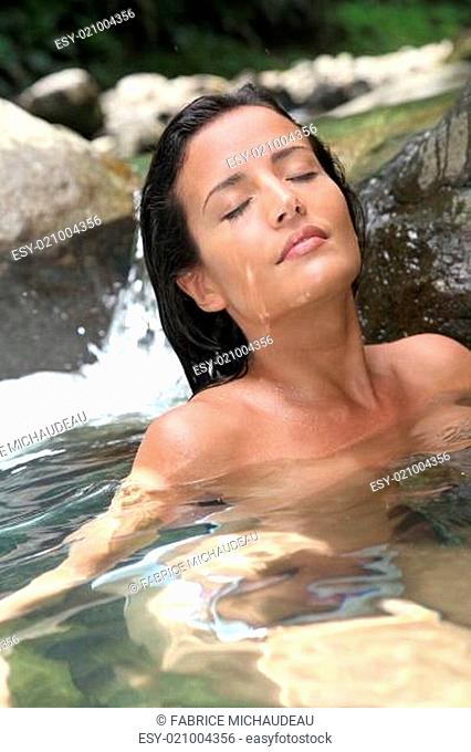 Attractive brunette woman taking a bath in river