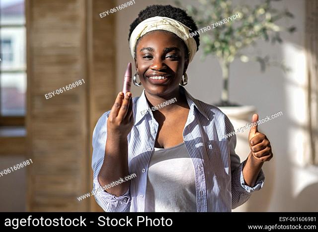 Beauty. Contented african woman in light clothes holding mascara