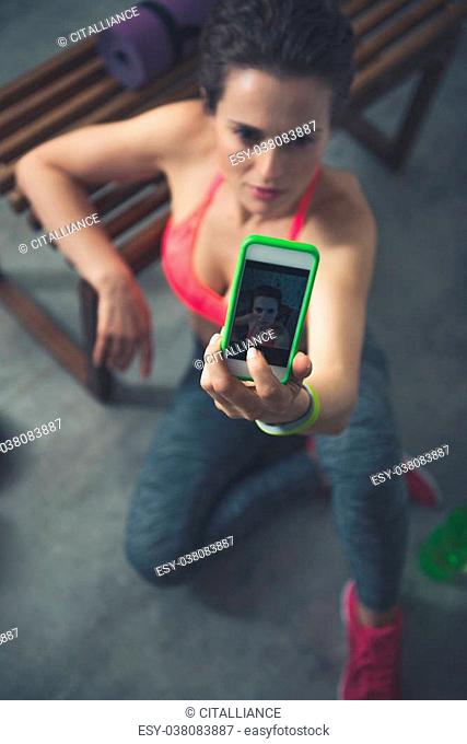 Body and mind workout in loft fitness studio. Closeup on fitness woman sitting in loft gym and taking selfies