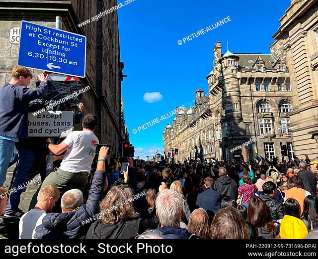 12 September 2022, Great Britain, Edinburgh: Onlookers try to catch a glimpse of the funeral procession with the coffin of Queen Elizabeth II across the Royal...