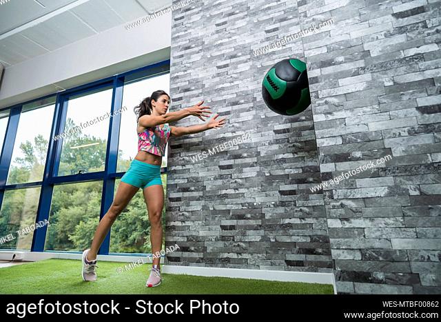 Female athlete throwing medicine ball at health club