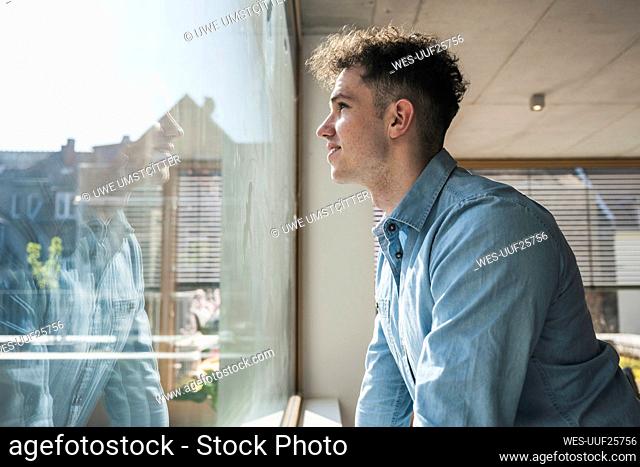 Young businessman looking out of window in office
