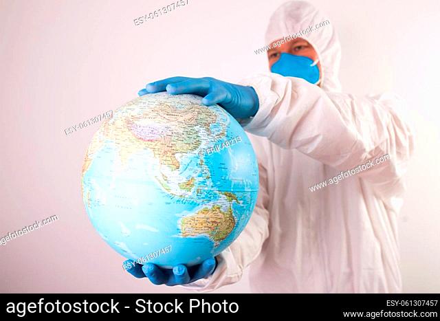 World epidemic danger concept. Male doctor man in medical face mask and gloves protecting planet Earth