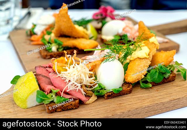 A close up view of delicious Smørebrød sandwiches on a wooden platter as a typical Scandinavian breakfast