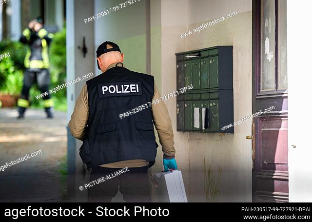 17 May 2023, Saxony, Chemnitz: A police forensic officer walks through the entrance of an apartment building on Kanalstraße in the Schlosschemnitz district