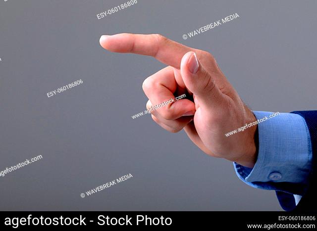 Midsection of caucasian businessman pointing with his finger, isolated on grey background
