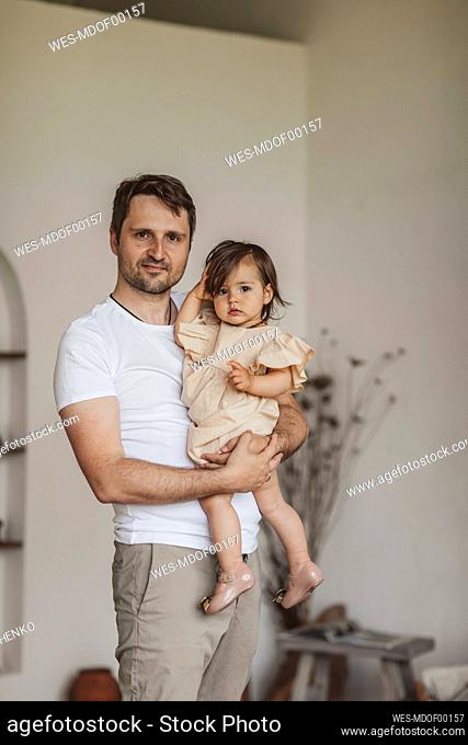 Man carrying cute daughter at home