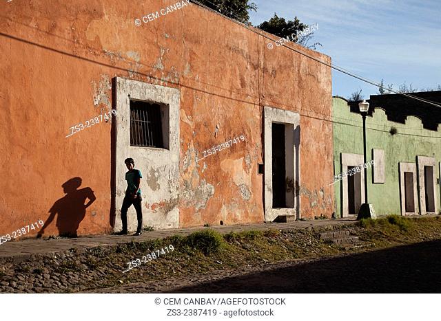 Young man walking in front of colorful colonial houses in El Alto District, Puebla, Puebla State, Mexico, Central America