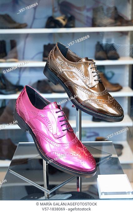 Two lace-up shoes in a shop window. Brown and pink