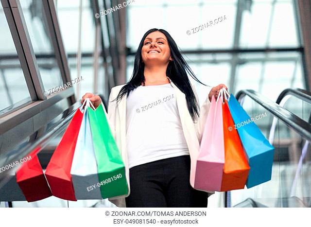 Beautiful young woman leaving the mall with plenty of shopping bags
