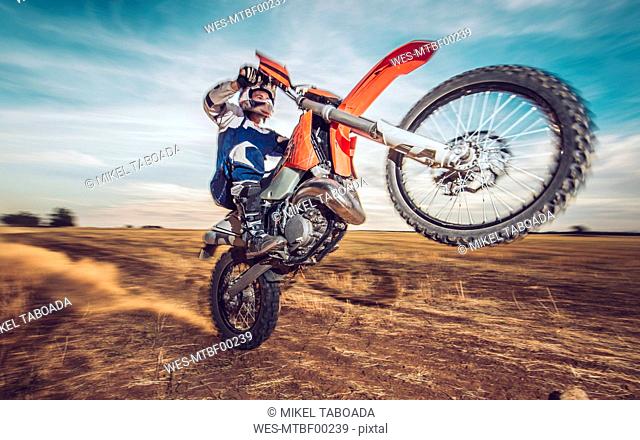 Motocross driver performing wheelie