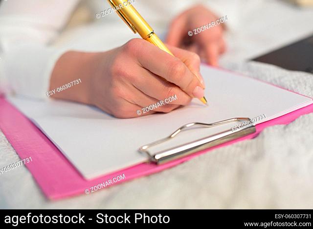 Woman hand making notes. Lying in bed. Business in bed concept