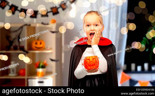 girl in halloween costume of dracula with pumpkin