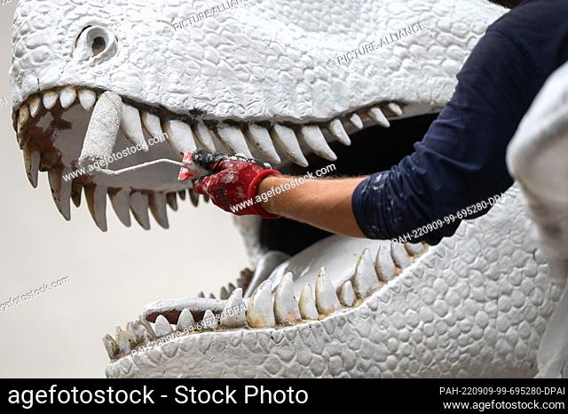 09 September 2022, Hessen, Frankfurt/Main: Marcel Walldorf, visual artist, paints the Tyrannosaurus Rex in front of the Senckenberg Naturmuseum with a white...