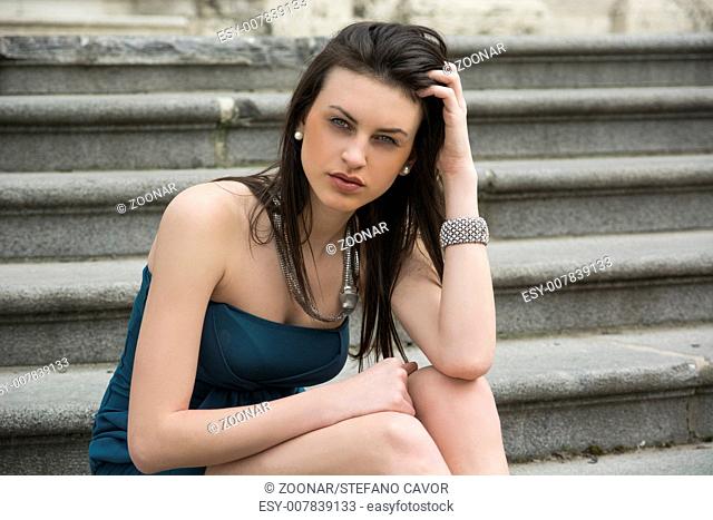 Elegant young woman sitting on stone steps outdoors