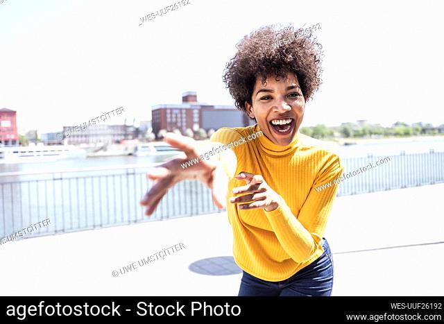 Cheerful woman with Afro hairstyle gesturing enjoying at promenade