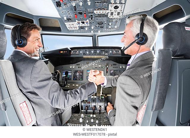 Germany, Bavaria, Munich, Businessmen piloting aeroplane from airplane cockpit