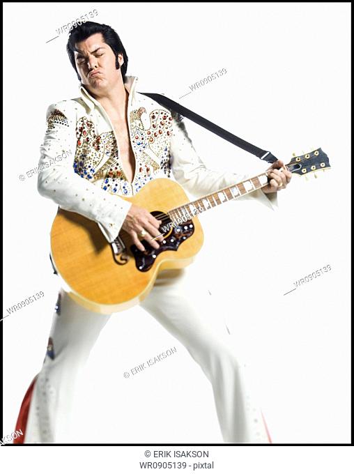 An Elvis impersonator playing the guitar