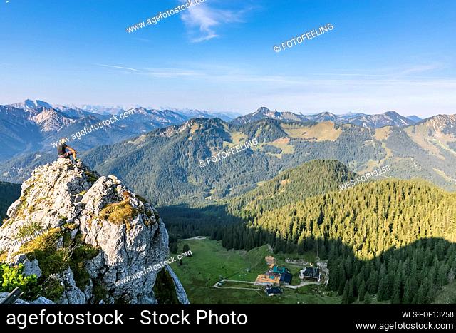 Germany, Bavaria, Male hiker sitting on summit of Taubenstein mountain