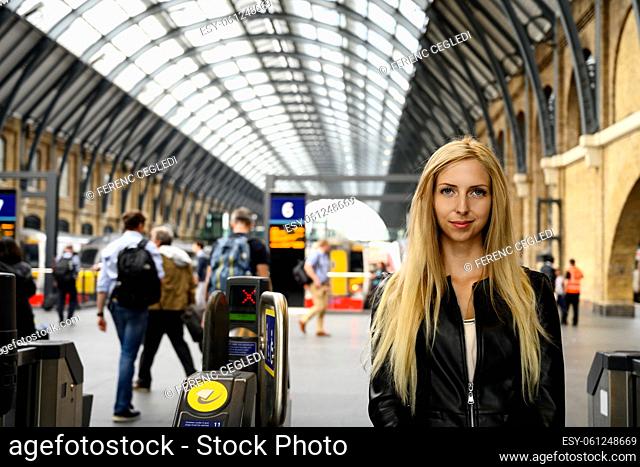 Close up portrait of an attractive smiling young woman with a train station in the background in downtown London, United Kingdom