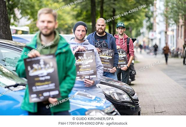Activists Konstantin Kubina (L-R), Martin Becker, Joachim Bick and Simon Chrobak hold posters while standing in a parking bay in Münster, Germany
