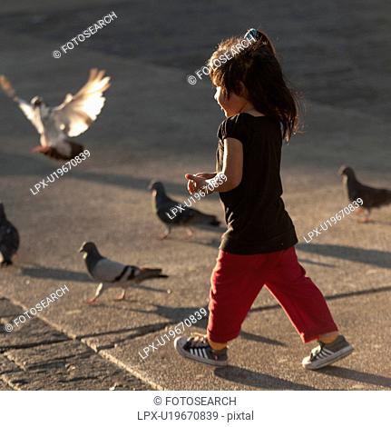 Girl walking near pigeons, Parque Central, Zona 1, Guatemala City, Guatemala