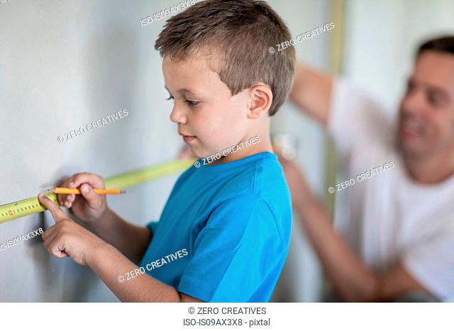Builder and son measuring wall