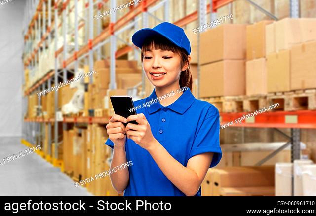 happy delivery woman with smartphone at warehouse