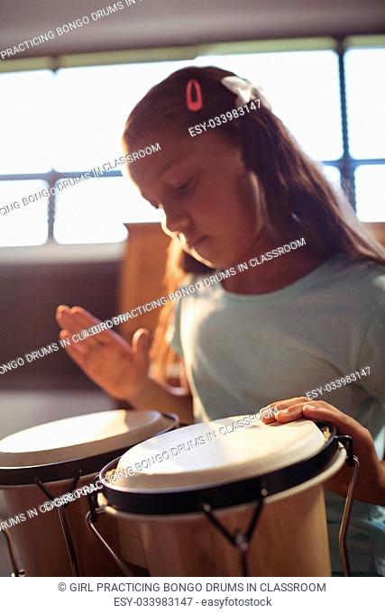 Girl practicing bongo drums in classroom at music school