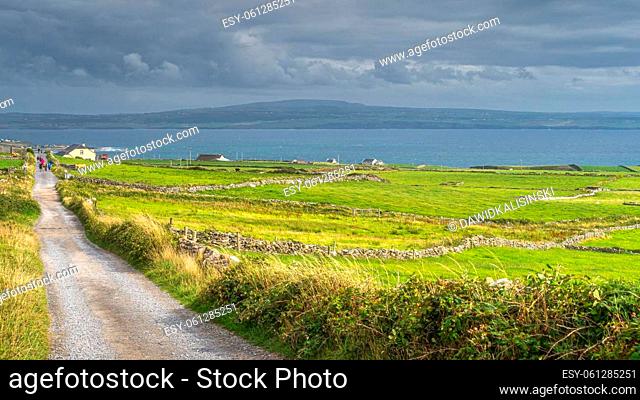 Tourists walking down the country road from popular attraction, iconic Cliffs of Moher, Wild Atlantic Way, County Clare, UNESCO, Ireland