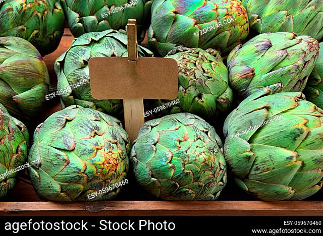 Artichokes: Closeup of a display of fresh artichokes at a farmers market stand, with blank price sign