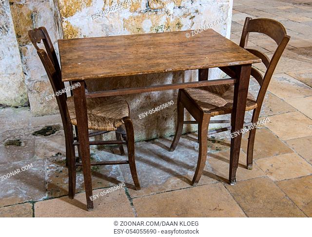 Wooden old table and two wooden chiars on a floor of old tiles