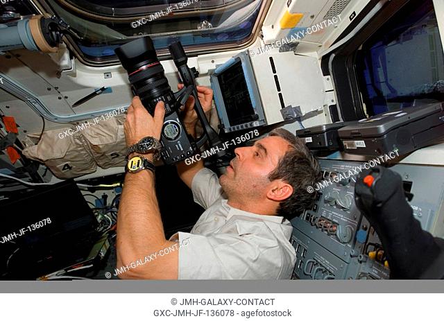 European Space Agency (ESA) astronaut Leopold Eyharts, STS-122 mission specialist, prepares to use a High Definition Video (HDV) camera